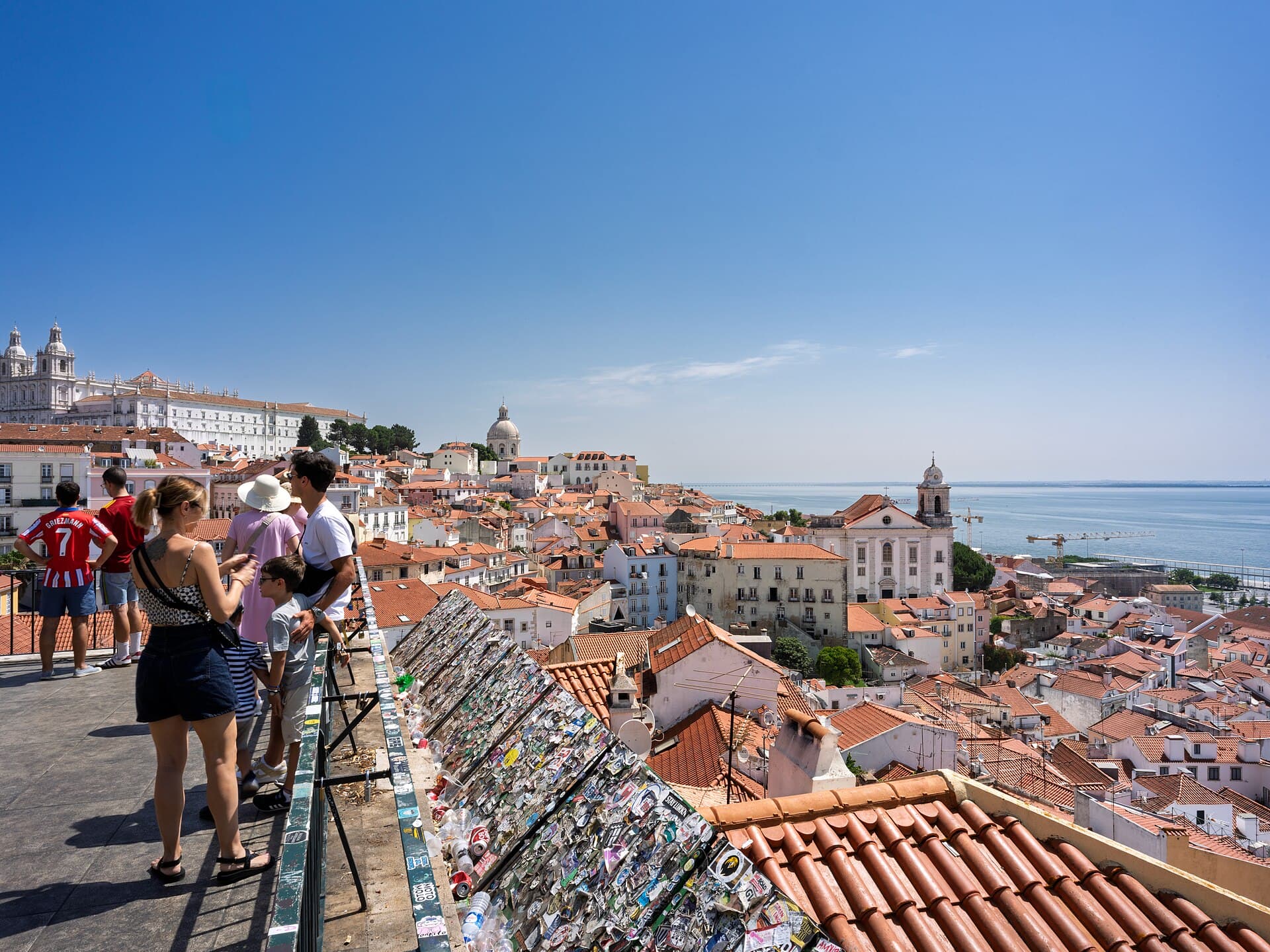 Visitors looking over Alfama rooftops from a Lisbon viewpoint